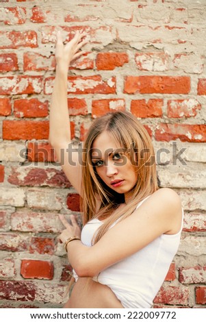 Young blonde hipster against red brick wall portrait