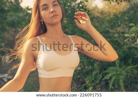 Women with her long blond hair fly in lthe wind. Head and shoulders outdoor shot in white tank-top
