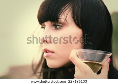 Relax outside. Young women face side view and glass of wine close up. Focus on glass.