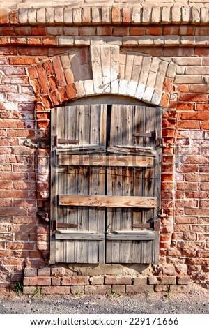 Old wooden window with its shutters closed on red brick wall.  Cracked house exterior, traditional architecture urban building in Astrakhan, Russia. Retro facade detail.