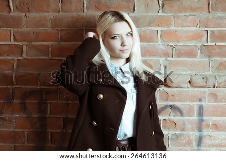 Beautiful hipster woman wear vintage jacket.Toned in warm colors. Outdoors shot, lifestyle.Colorized image of young hipster girl with long blond hair looking at camera copyspace on the red brick wall.