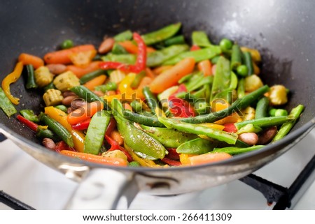 Closeup image of roasting mexican vegetables mix in wok pan side view, shallow DOF. Mexican or chinese cuisine.