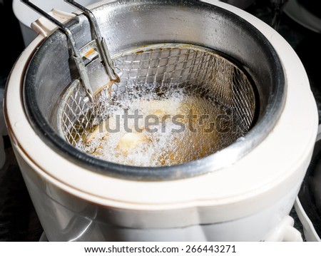 French fries cooking and bubbling in a deep fryer filled with oil. From above view.