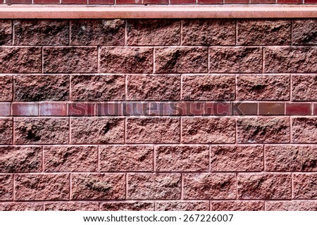 Background of red wall pattern texture backdrop wallpaper. Wall is covered with decorative bricks or tiles with texture effect. Sun is up and left of the wall.