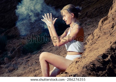 Women sitting on sand with cloud of white dust fly around.