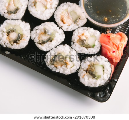 Sushi from above. Eel rolls served on a fast food pack with open cover. Soy sauce and red ginger. Copyspace for inscriptions.