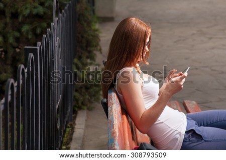 Female student work in internet outdoors. Education in city park. Mobile communication. Remote office. Copyspace for text/ Side view. She look at screen.