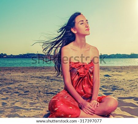Long haired brunette meditate on sandy beach with flattering hair fly with the wind