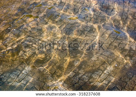 Light and shadow play on paved fountain bottom background. Shallow clear water of old fountain.
