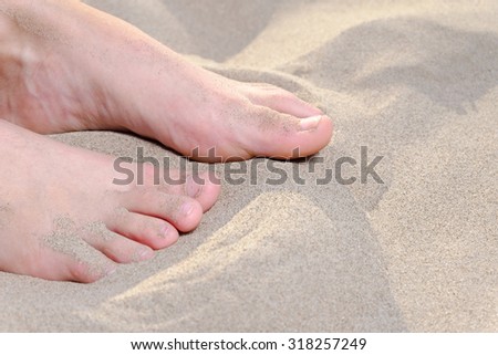 Macro of teen girl feet (no nail polish) on sand and space for text, natural nails