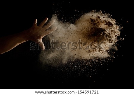 Throwing a Handful of brown earth in the air - isolated on black background