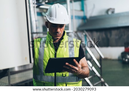 Engineer foreman using digital tablet to repair machine in industrial factory. worker in safety uniform working at construction site. heavy technology industry concept Photo stock © 