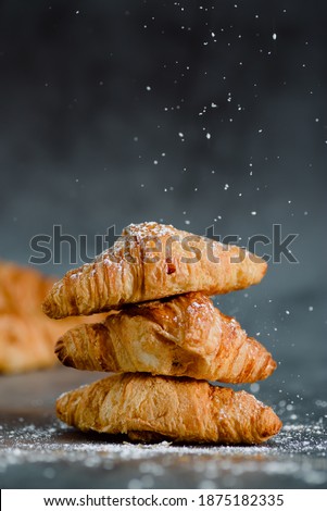 Close up of pile of delicious croissants on a dark background. Homemade croissants. Sugar glass falling. Vertical.
