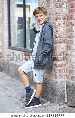 Young boy wearing headphones against wall, portrait