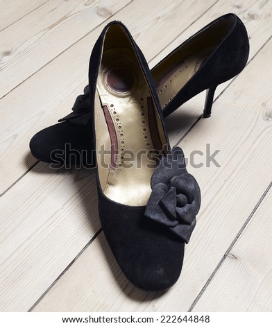 Stylish black high heels in wooden floor