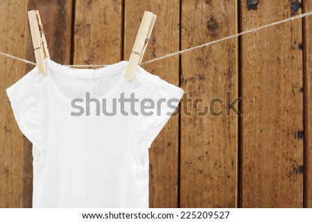Babywear hanging on washing line against wooden background