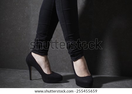 Woman posing in high heels in studio, low section
