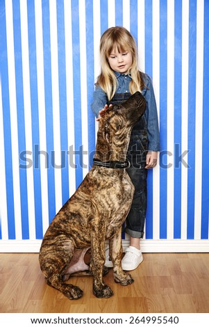 Girl petting her large dog in striped room