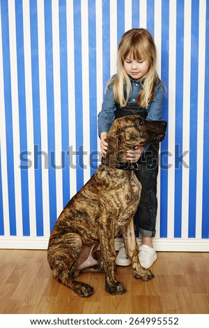 Girl holding large dog in striped room