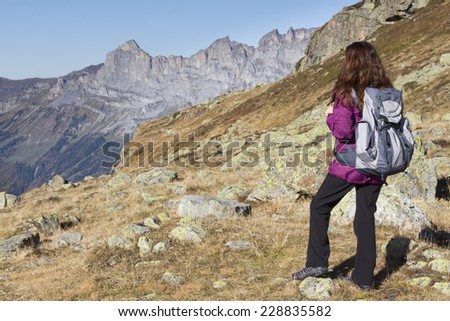 Woman hiking on Swiss Alps watching the mountain landscape