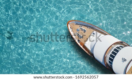 Aerial drone top down photo of luxury exotic yacht nose with wooden deck anchored in paradise turquoise bay