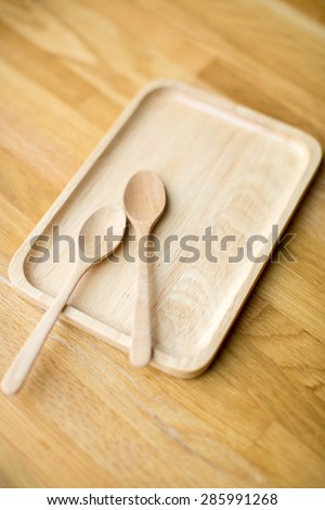 Wooden tray and spoon on a wooden table top with selective focus