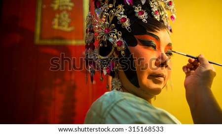 BANGKOK, THAILAND- OCT 25, 2014: Chinese opera actress is wearing her makeup at backstage before the performance begin.