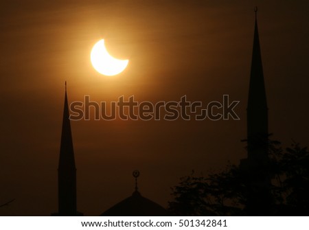 A partial solar eclipse on the top of Sultan Salahuddin Abd Aziz dome and minarets mosque as state mosque in Shah Alam, Selangor Malaysia.