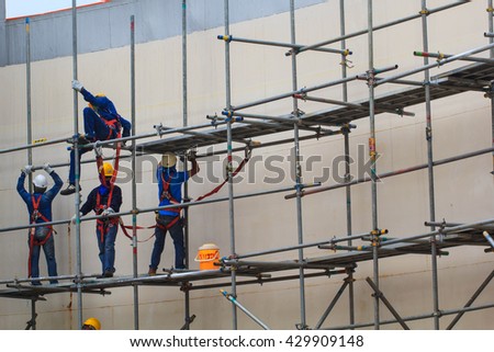 Four construction workers setting up scaffolding