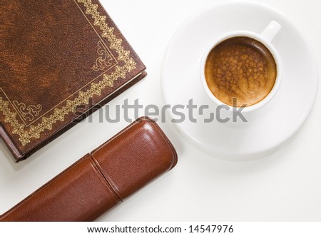 Overhead shot of a cup of coffee, part of a book and part of a glasses case on white background. All in focus.