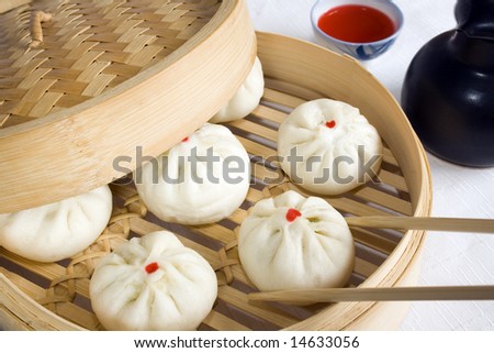 Bunch of vegetarian stuffed dumplings on a bamboo steamer. Main focus on the dumpling with chopsticks.