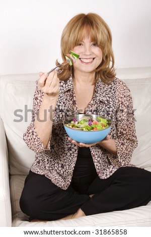A beautiful, healthy 65 years old senior woman eating salad. No surgeries, 100% natural beauty and healthy eating.