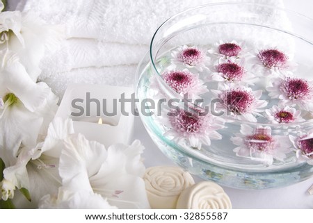 A relax and beauty image, composed by white towels, soap bars, candle and flowers.