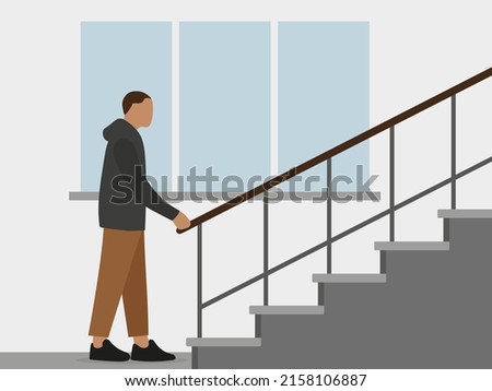 A male character stands near the stairs and holds on to the railing against the background of a wall with a window