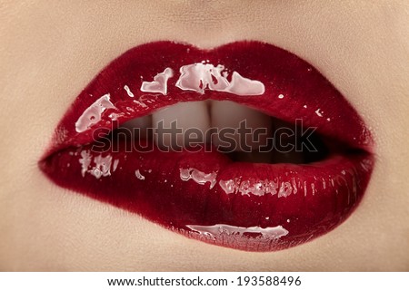 Beautiful female with red shiny lips close up.