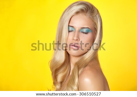 Beautiful portrait of a young girl with bright make-up on a yellow background.