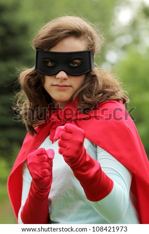 Serious young woman wearing a red super hero kit with a black mask is ready to attack