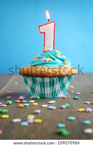 Number one birthday candle on a blue cupcake on blue background