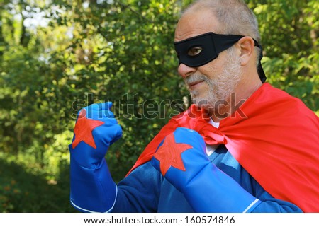 Serious senior super hero with black mask having crossed arms