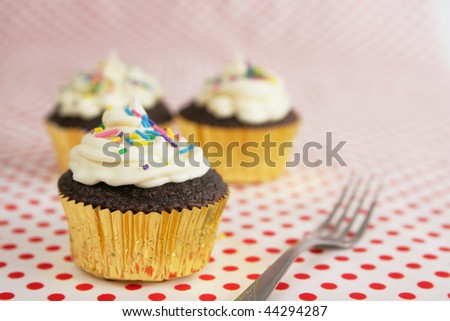 three chocolate cup cakes with candies