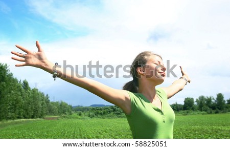Portrait of a teenager girl with arms wide opened in a green meadow
