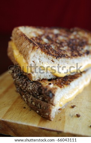 Grilled cheese sandwich with melted cheese on wood plate