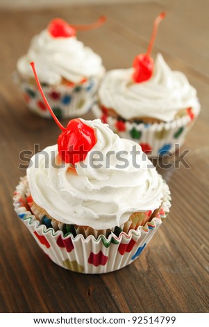 Cupcakes with  vanilla icing and cherry on top