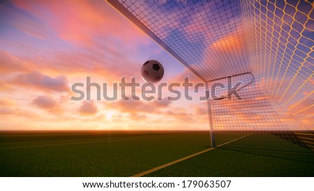 Soccer ball was floated into the goal on the football field at sunset.