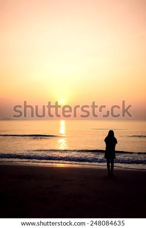 silhouette of woman alone and wave on the beach with sunset in the sea