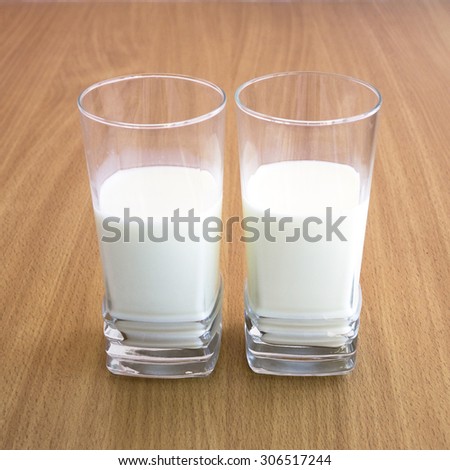 A fresh cold milk in high transparent glass. Let us eat cake with milk.