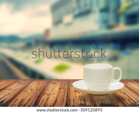 Steaming coffee cup on window background. A view of The train tracks.