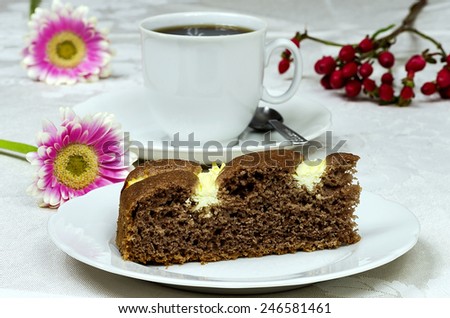 Homemade cocoa cake with cream cheese cup of coffee and flowers