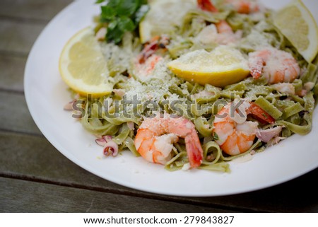Dish of spinach tagliatelle pasta with king prawn, other seafood, oregano, rosemary, and grated grana padano cheese.
