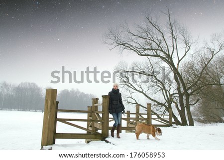 Young beautiful woman with an English bulldog for a walk in winter park